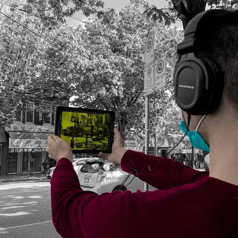 A man holding up a tablet to experience 360 Riot Walk in Chinatown