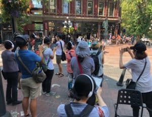People using 360 Riot Walk on their tablets in the street. Guided Tour, Stop 1: Maple Tree Square (and Gassy Jack)